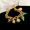 Gold chain bracelet featuring an ocean pearl, starfish, and green leaf charms.
