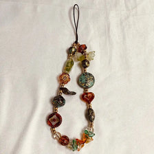 A necklace made of various colored beads with a black cord and a small charm.