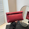 Primer plano de un bolso de mano acolchado y tejido rojo sobre una superficie de vidrio.