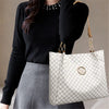 A woman holds a large white geometric tote bag with a gold logo against a neutral background.