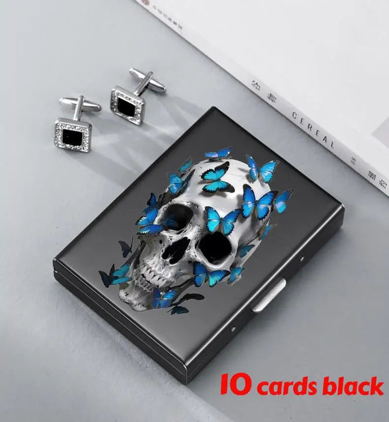 A black slim card holder featuring a skull design with blue butterfly accents, next to silver clip earrings.