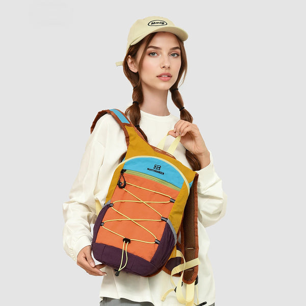 A woman wearing a beige cap holds an orange and purple lightweight travel hiking backpack.