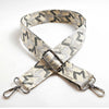 A beige and gray jacquard patterned strap for a crossbody bag featuring an adjustable buckle.