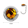 Round acrylic foldable hook with a golden amber-colored top and silver metal ring.