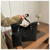 A black leopard print tote bag with a leather handle is being held by a person on a wooden surface.