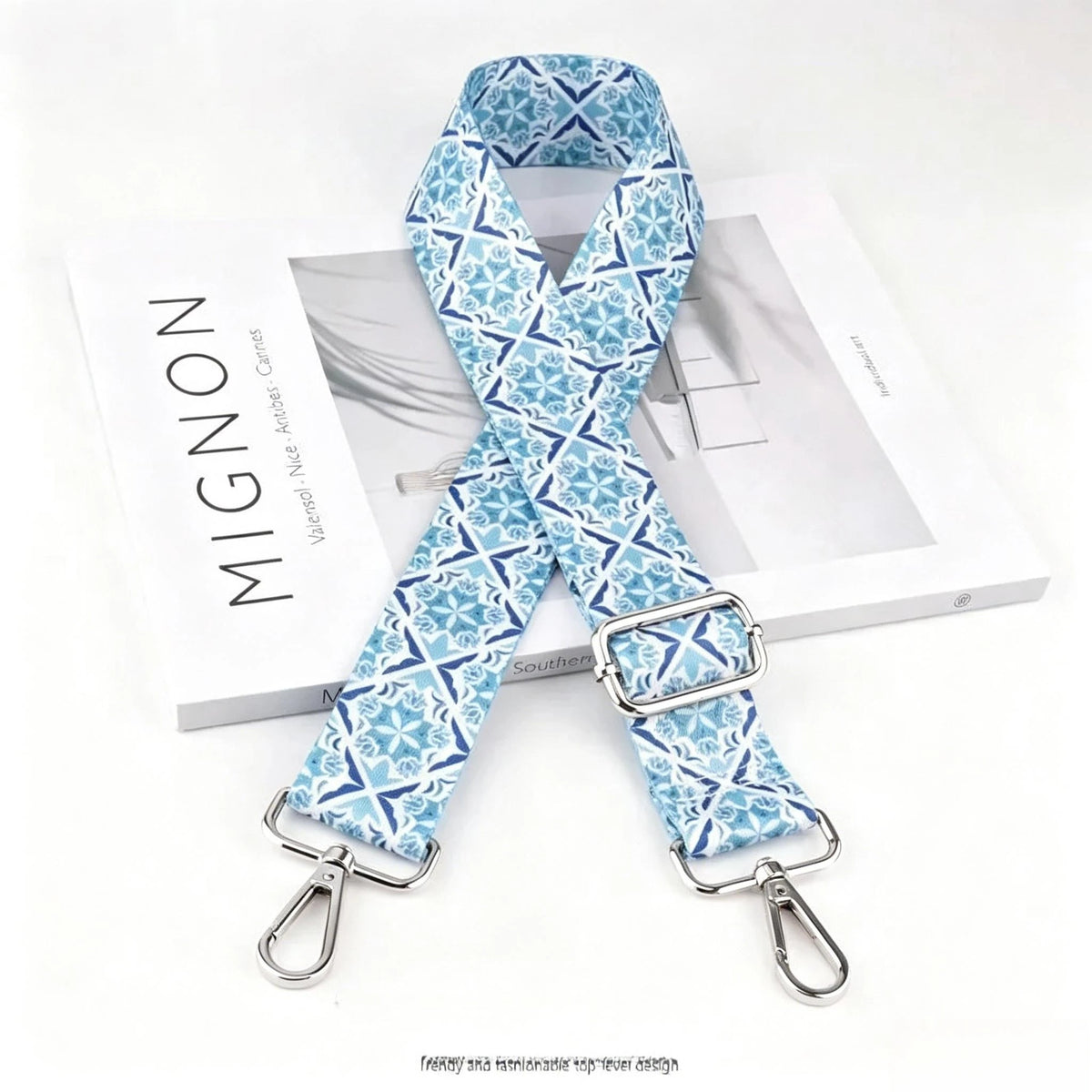 A light blue and white patterned nylon crossbody bag strap with a silver metal buckle.
