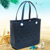 A dark blue portable EVA beach tote bag resting on golden sand with starfish and seashells.