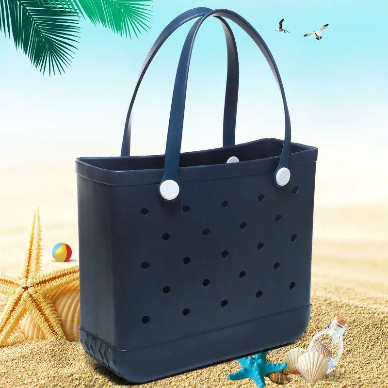 A dark blue portable EVA beach tote bag resting on golden sand with starfish and seashells.