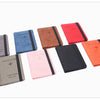 A collection of ten passport holders in various shades including gray, blue, red, orange, and pink.