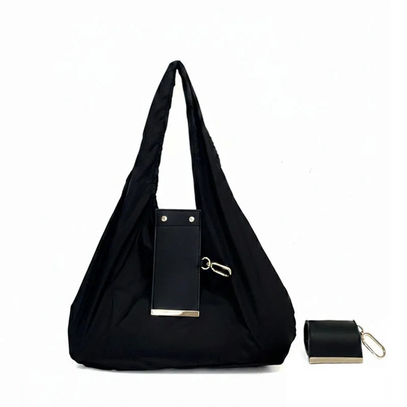 Sac de shopping pliable en nylon noir avec des détails en laiton.