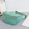 A mint green multi-layer sports waist bag with a zipper and gold accent, resting on a checkered surface.