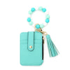 A turquoise leather card holder with a beaded tassel keychain attached.