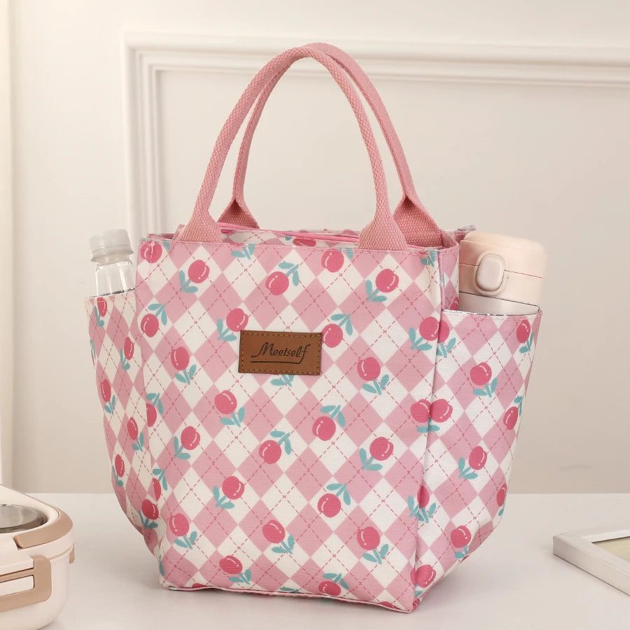Bolsa térmica a cuadros rosa para almuerzo y pañales mostrada sobre una superficie blanca.