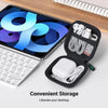 Una caja de almacenamiento negra contiene AirPods blancos y accesorios junto a una laptop plateada.