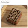 A brown leopard print double zipper wallet displayed on a wooden surface.