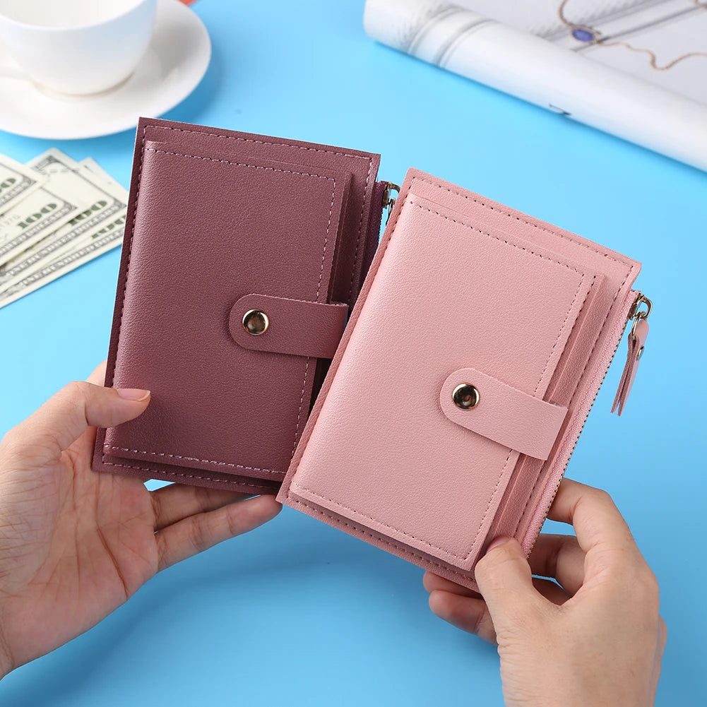A hand holds a pink leather wallet with card holder and coin pocket on a light blue surface.