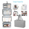 A gray travel toiletry bag with a hanging hook, open to show various skincare and beauty products.