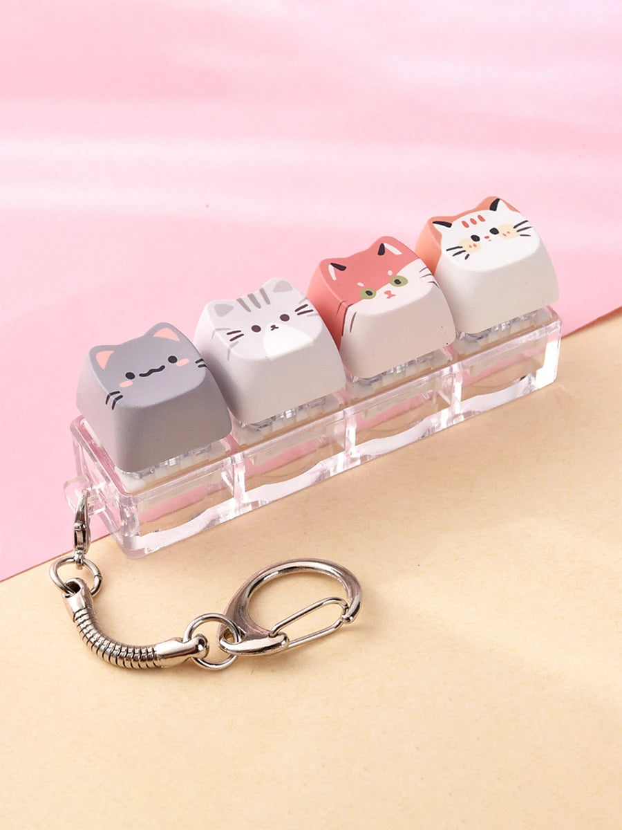 A row of pink and white kawaii cat keycaps fidget toys displayed on a clear plastic tray with a silver bag charm.