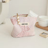 A pink floral canvas makeup bag with gold hardware and a tag resting on a white surface.