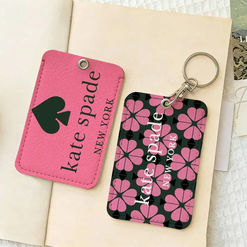 A pink and black flower patterned card holder keychain featuring the text Kate Spade New York.
