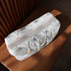 A white cosmetic storage pouch with a light pattern of cute cats resting on a wooden surface.
