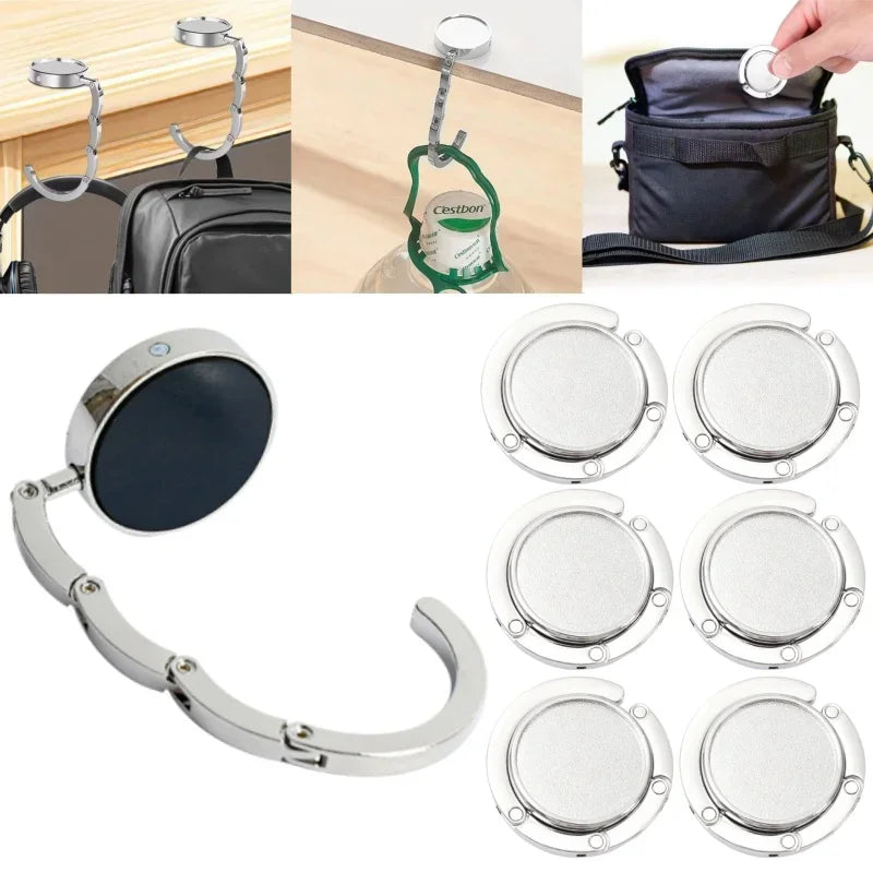 Un juego de ganchos plegables de bolsa plateados y un espejo redondo para organizar carteras y bolsos.