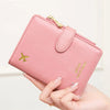 A hand holds a pink multi-functional PU leather passport wallet with gold accents and a small airplane emblem.