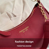 A close-up of a red leather shoulder bag with gold chain hardware and stitching, featuring the text Fashion design.