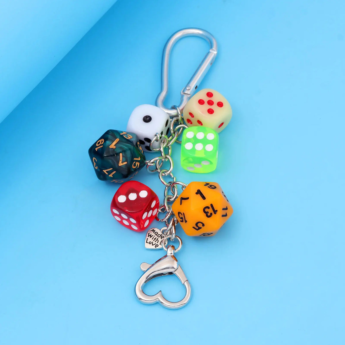 A silver keychain charm featuring various colored dice and a heart shape.