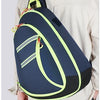 A person is wearing a navy blue medical crossbody bag with neon yellow accents over a light-colored shirt.