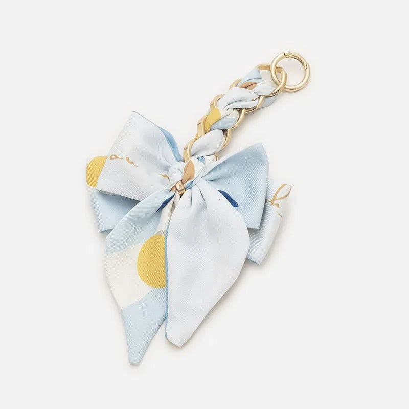 Light blue fabric bow with gold chain strap extension for a handbag accessory