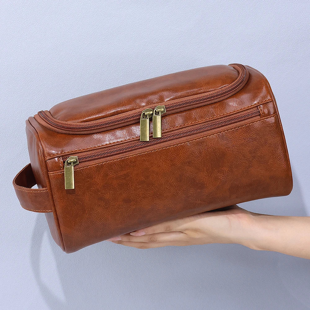 Braune Vintage PU-Leder-Toiletrytasche mit Reißverschluss und Aufhänger, gehalten von einer Hand.
