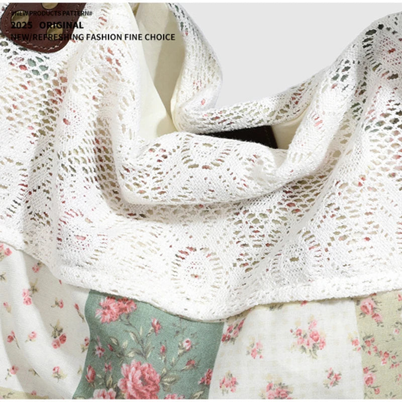 Close-up of a white crocheted lace scarf or shawl with pink floral details, displayed against a patchwork fabric background.