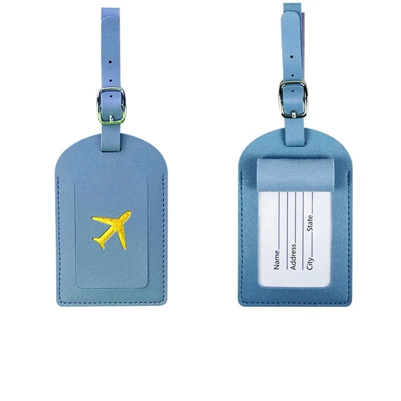 A pair of light blue PU leather luggage tags with silver clasps and white identification fields.