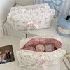 A white and pink floral cosmetic storage pouch with a ruffled edge is displayed on a white surface.