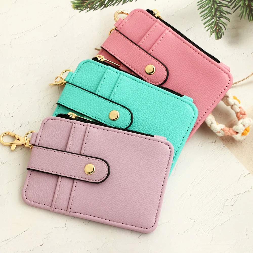 Three stacked silicone PU leather key chain wristlet wallets in pink, mint green, and lavender on a white background.