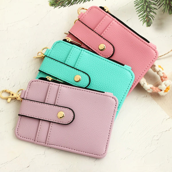 Three stacked silicone PU leather key chain wristlet wallets in pink, mint green, and lavender on a white background.