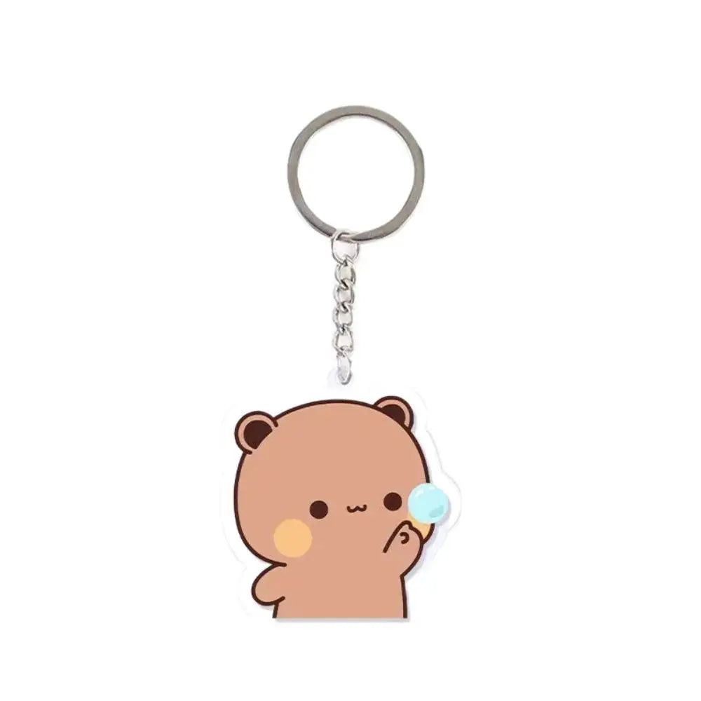 A round silver keychain charm with a small brown cartoon bear figure.