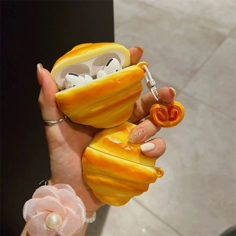 A hand holds a silicone protective case shaped like a yellow, wavy pod, containing white wireless earbuds.