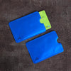 A blue RFID protection card sleeve with a green card inserted, resting on a dark surface.