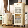 A beige foldable laundry basket with mesh panels and handles is shown on a wooden floor.