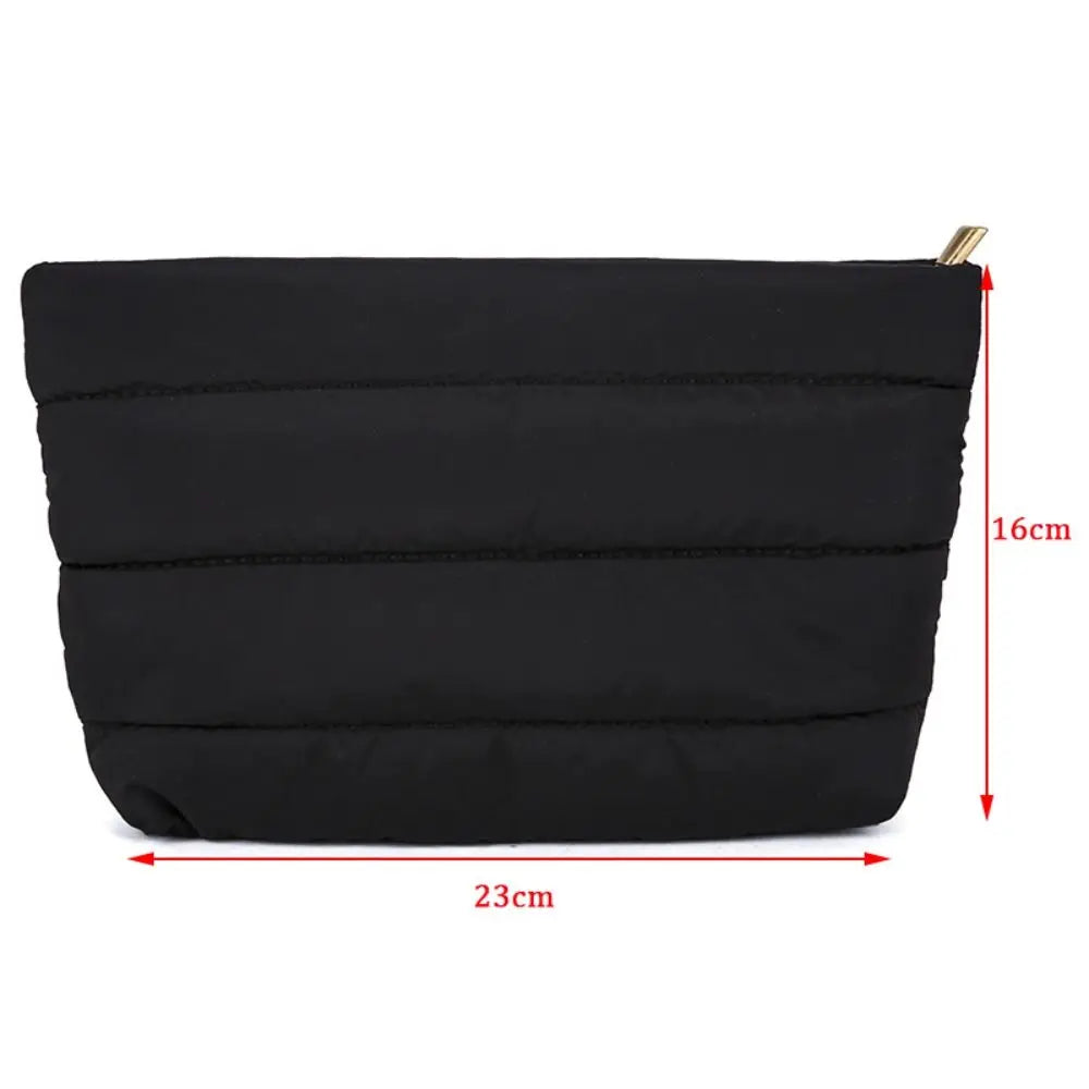 Black quilted cosmetic travel bag with a gold zipper and dimensions 16cm by 23cm.