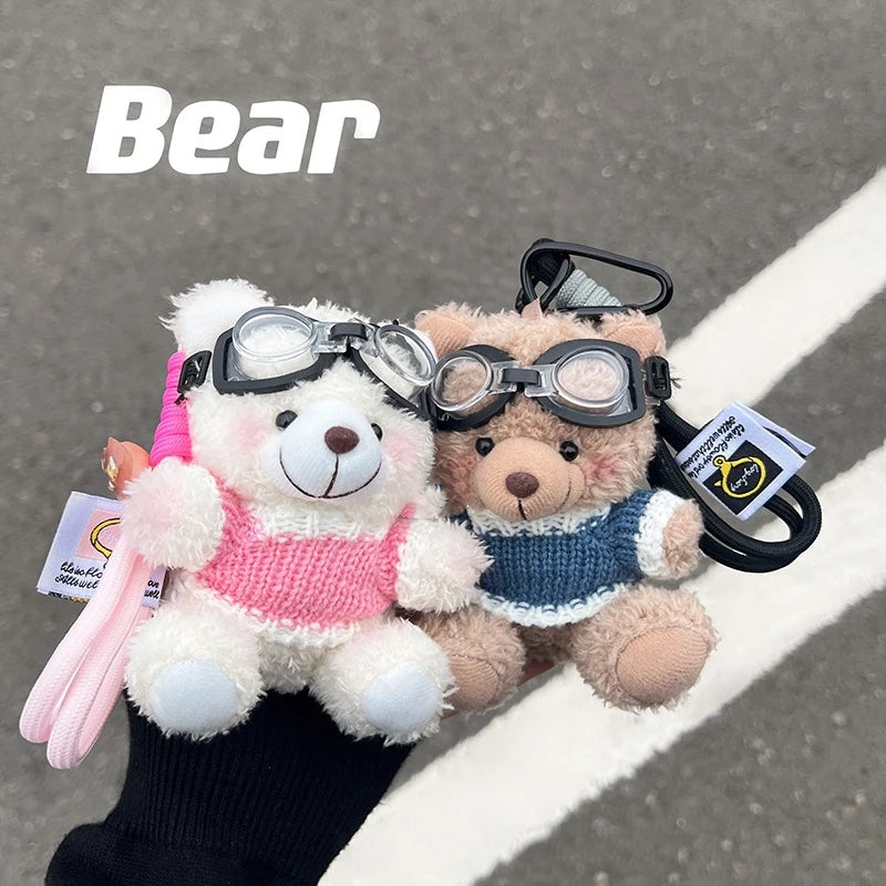 A white plush bear holding a pink ribbon and another brown plush bear with glasses attached to a keychain.