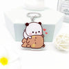 A clear resin keychain charm of a cute white and brown cartoon bear character resting on a white box.