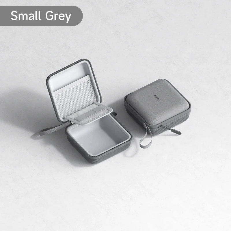 Una pequeña bolsa portátil gris para organizar cables, abierta junto a una cerrada, sobre una superficie blanca.