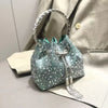 A sparkling teal crystal-embellished evening clutch with a silver chain hanging from the top.