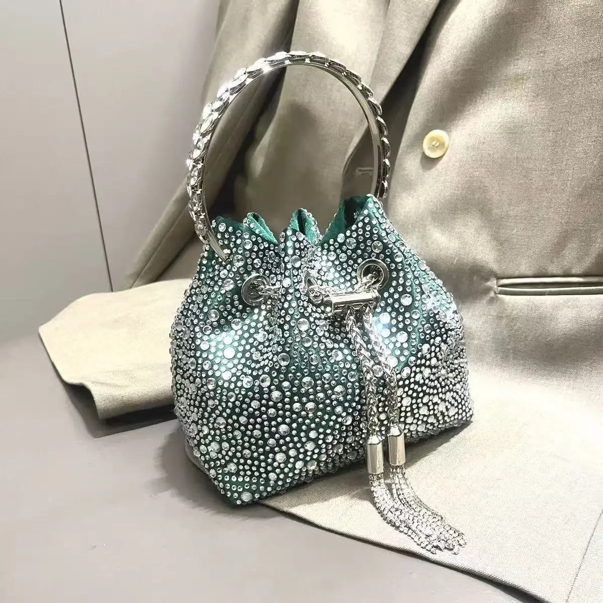 A sparkling teal crystal-embellished evening clutch with a silver chain hanging from the top.