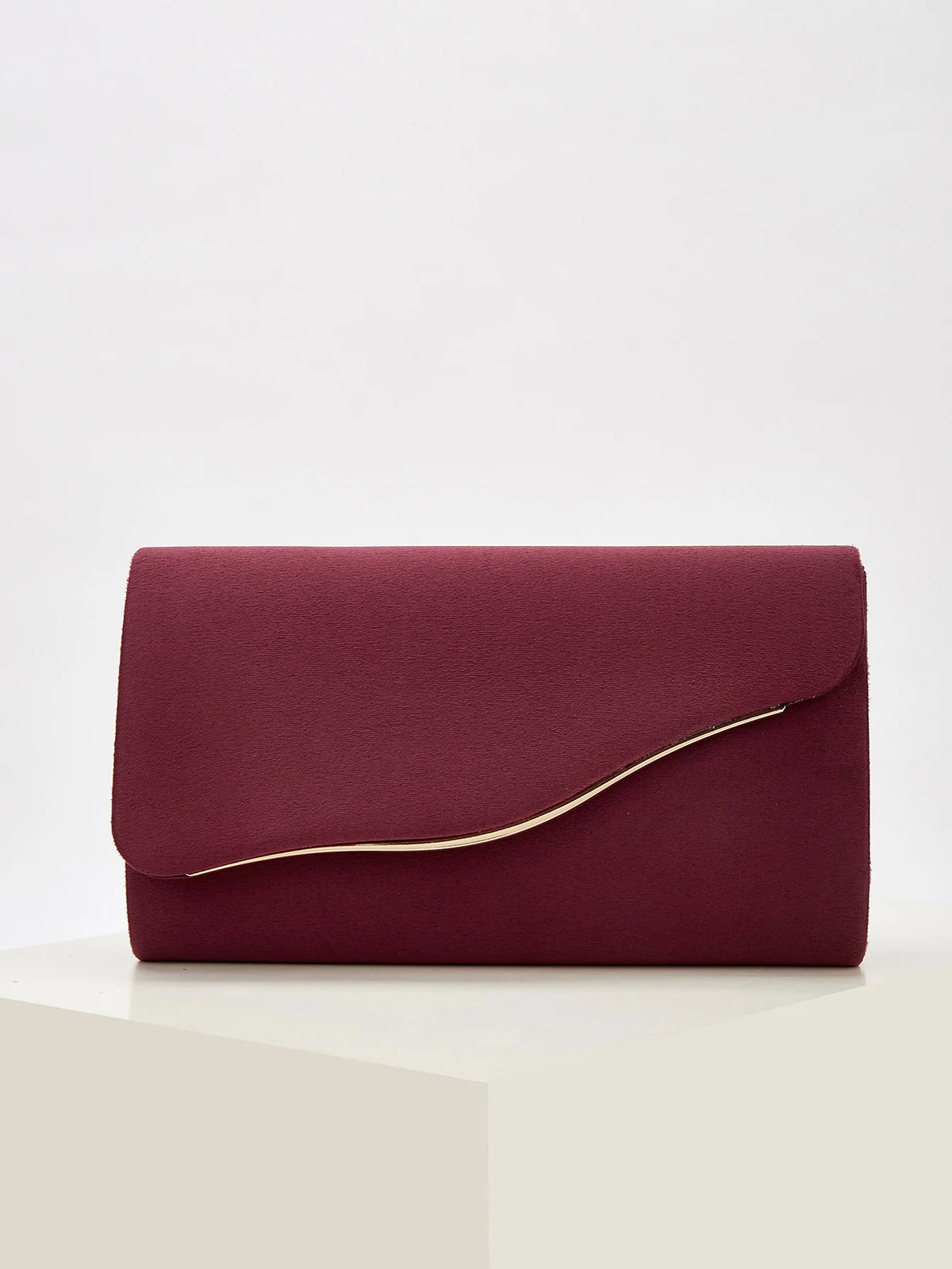 A deep burgundy velvet evening clutch with a smooth finish and a visible gold-colored edge.