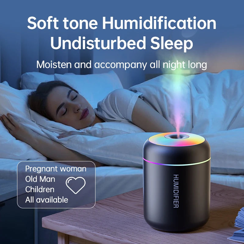 A black humidification device is placed on a wooden table next to a woman sleeping in bed.