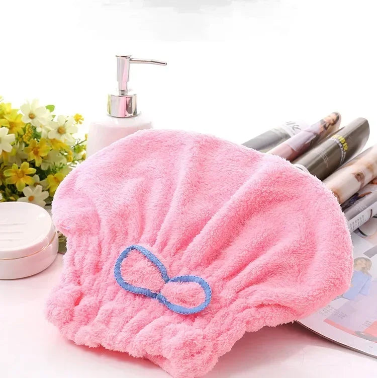 Lazo de microfibra rosa para el pelo y toalla de baño junto a un dispensador de jabón.